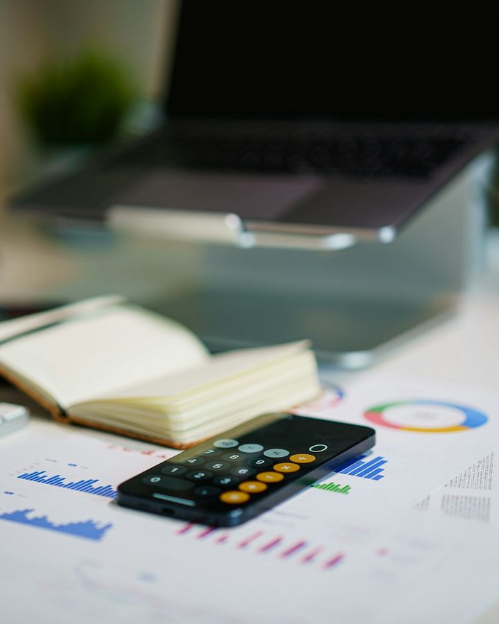 Mesa de trabalho com relatórios financeiros, calculadora e caderno